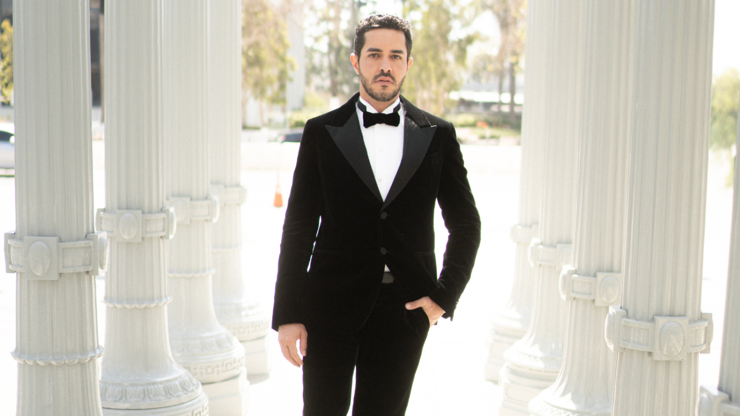 João Brasio em traje formal (black tie) em ambiente com colunas clássicas, associado a eventos internacionais do entretenimento