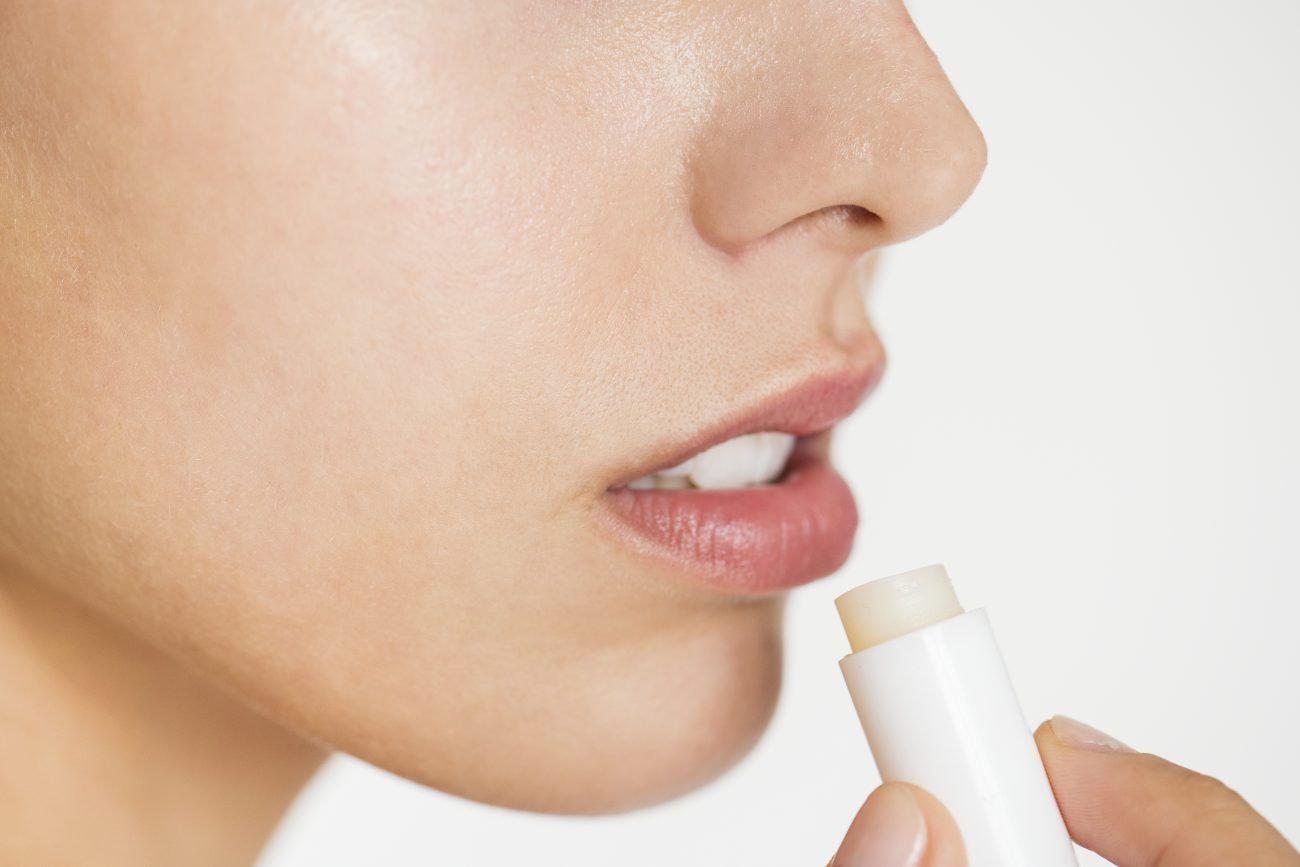 Mulher testando um dos produtos baratos que salvam os lábios no inverno