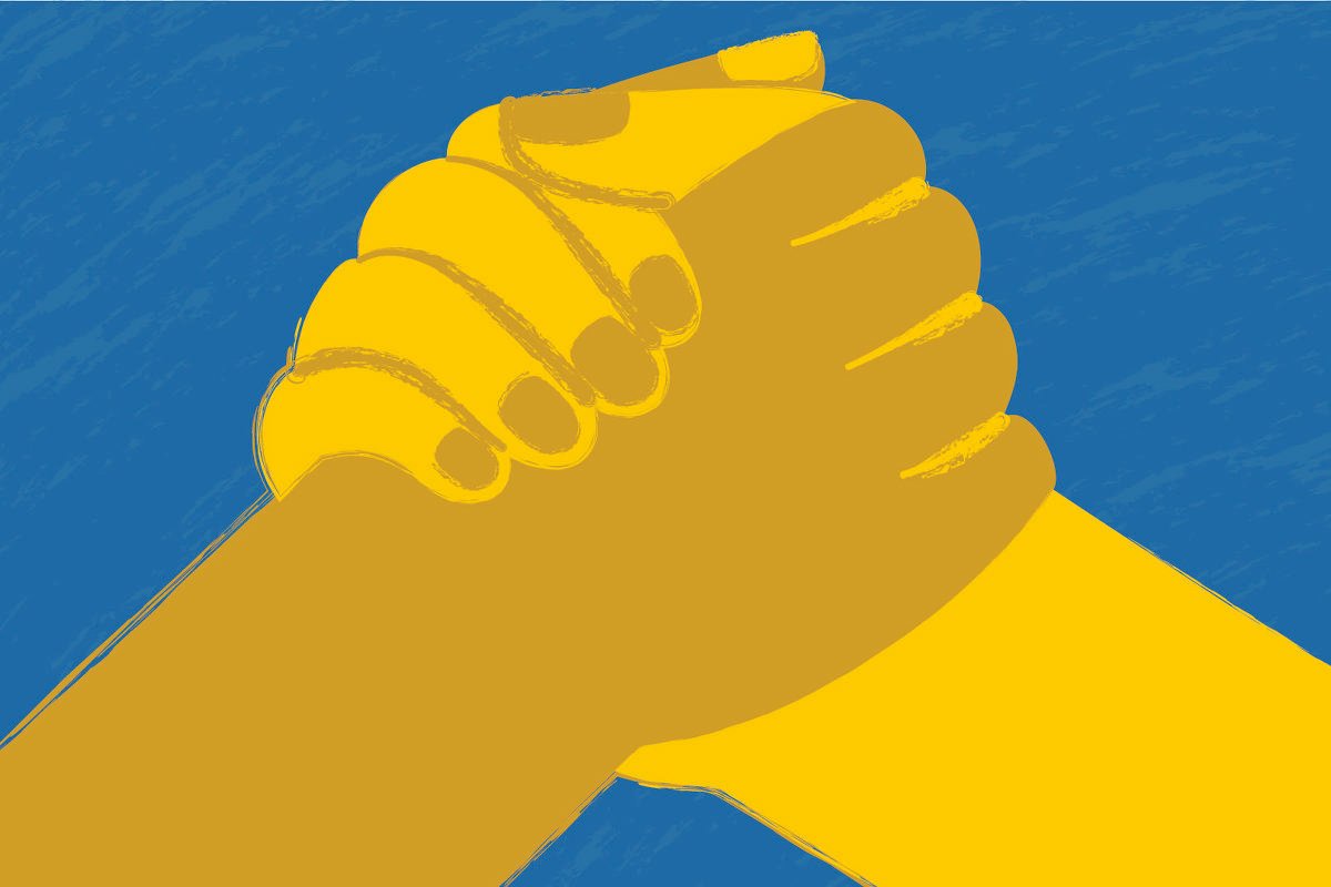 Sob um fundo azul claro surgem duas mãos, com diferentes tons de amarelo, se cumprimentando de modo firme. 
